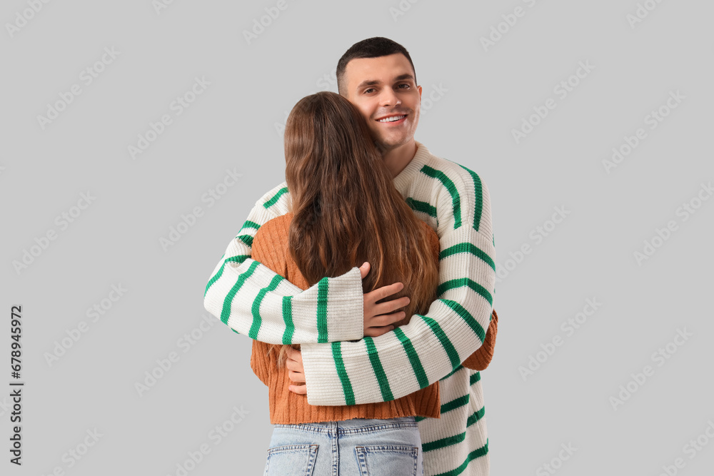 Young couple hugging on light background