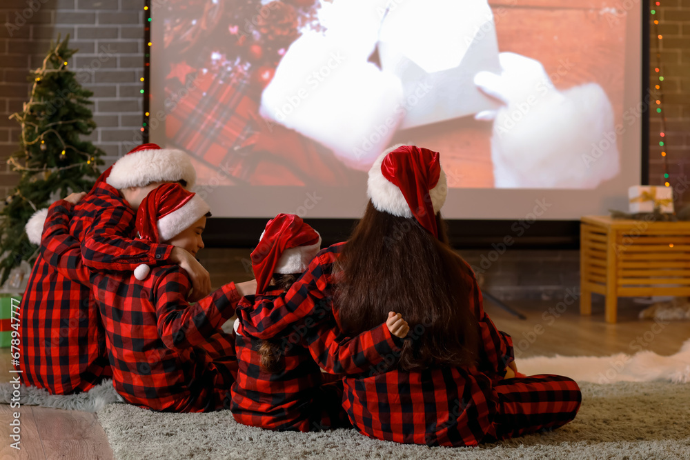 Happy family watching Christmas movie on projector screen at home, back view