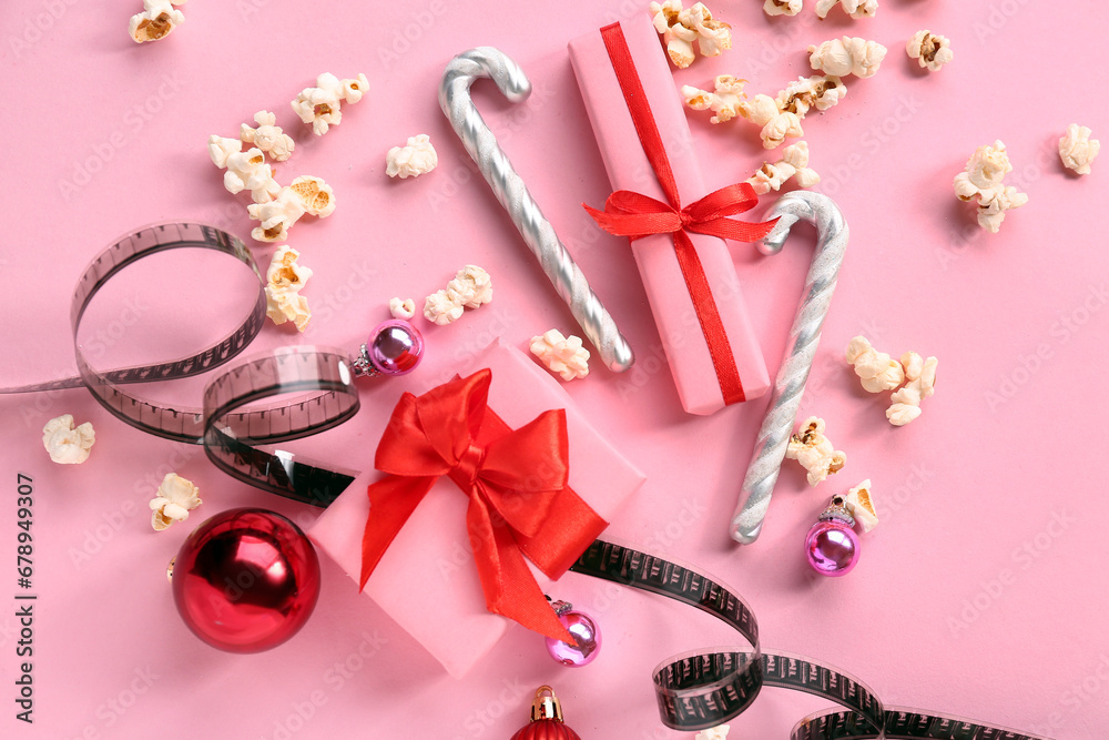 Popcorn with film reel and Christmas decor on pink background