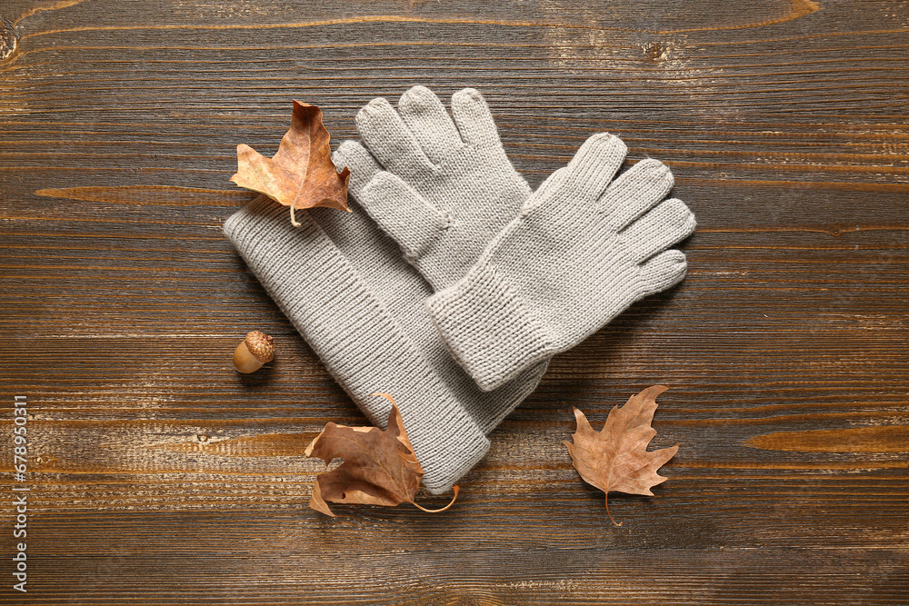 Gloves with warm hat and leaves on wooden background