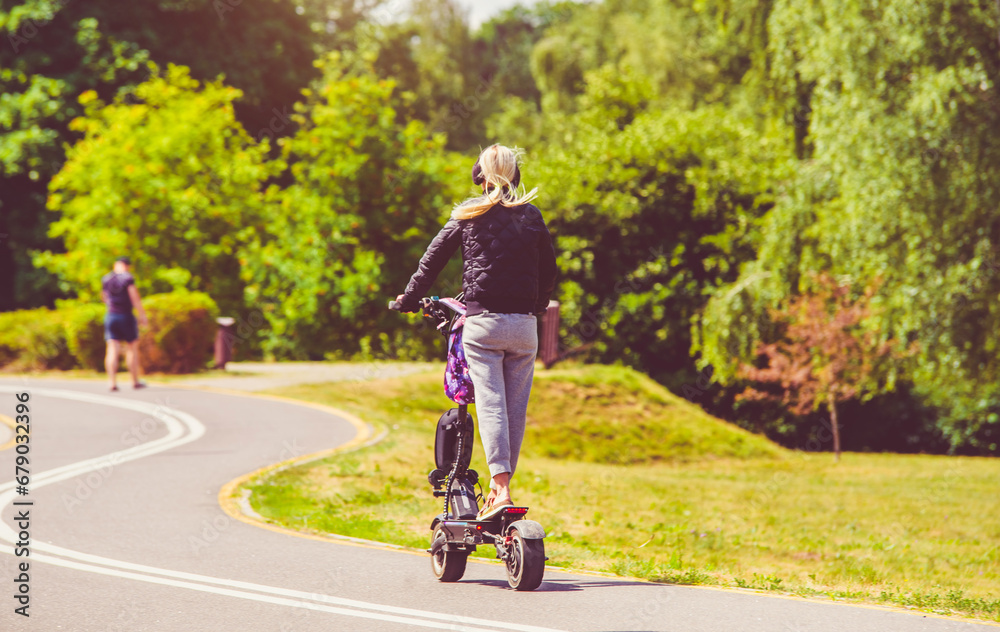 Girl rides an electric scooter in the summer Park 