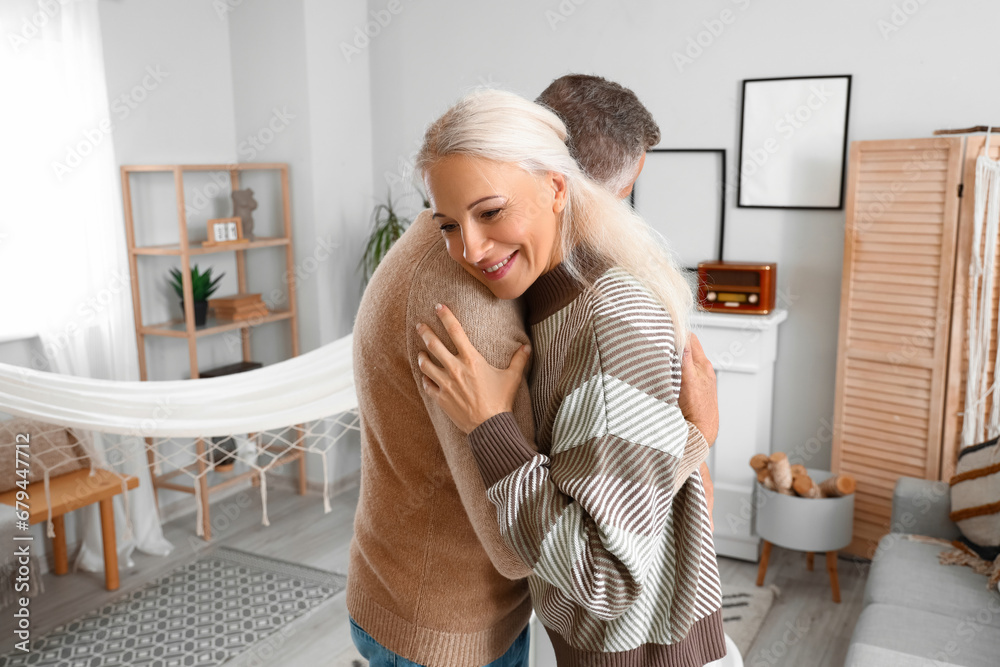 Mature couple dancing near fireplace at home