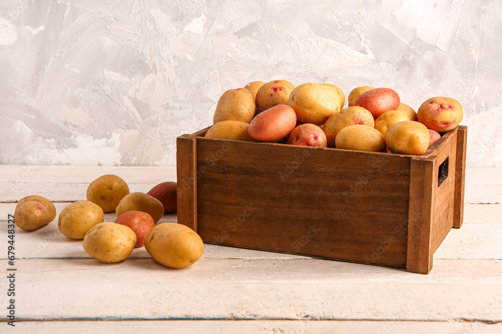 Box with fresh raw potatoes on white wooden table