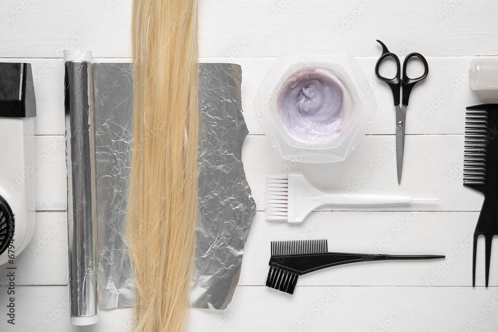 Bowl with hair dye, set of hairdressers tools and blond strand on white wooden background