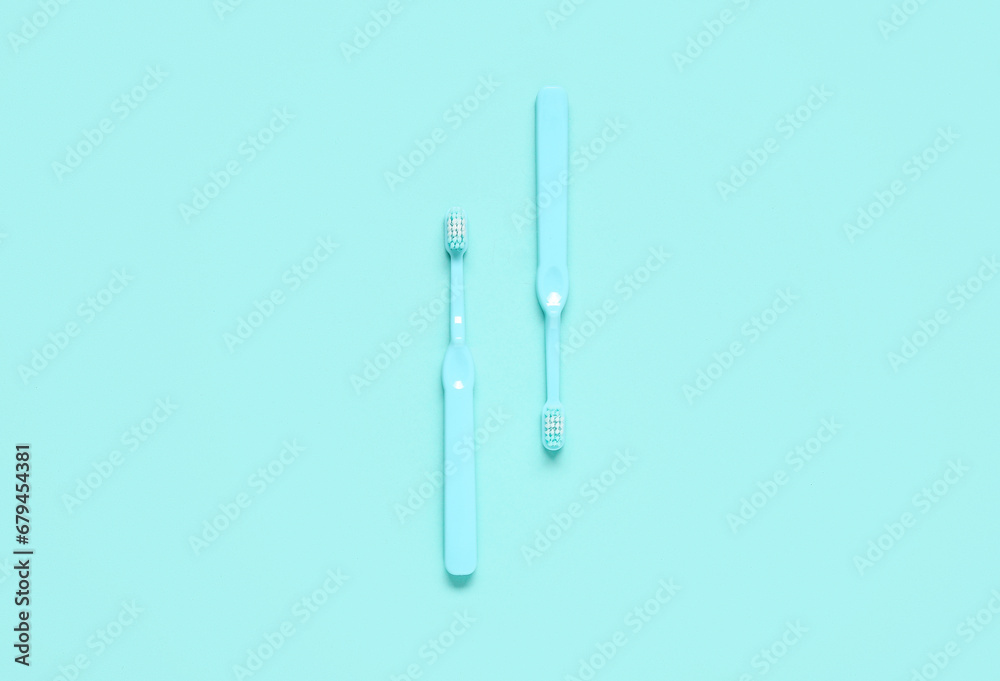 Two blue toothbrushes on color background.