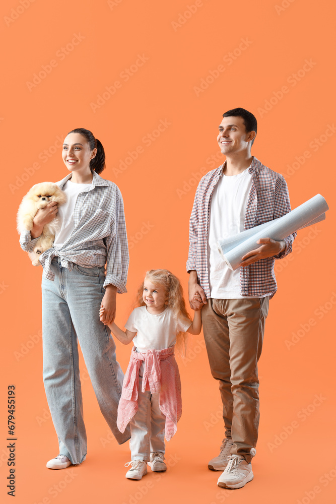 Happy family with wallpaper rolls on orange background