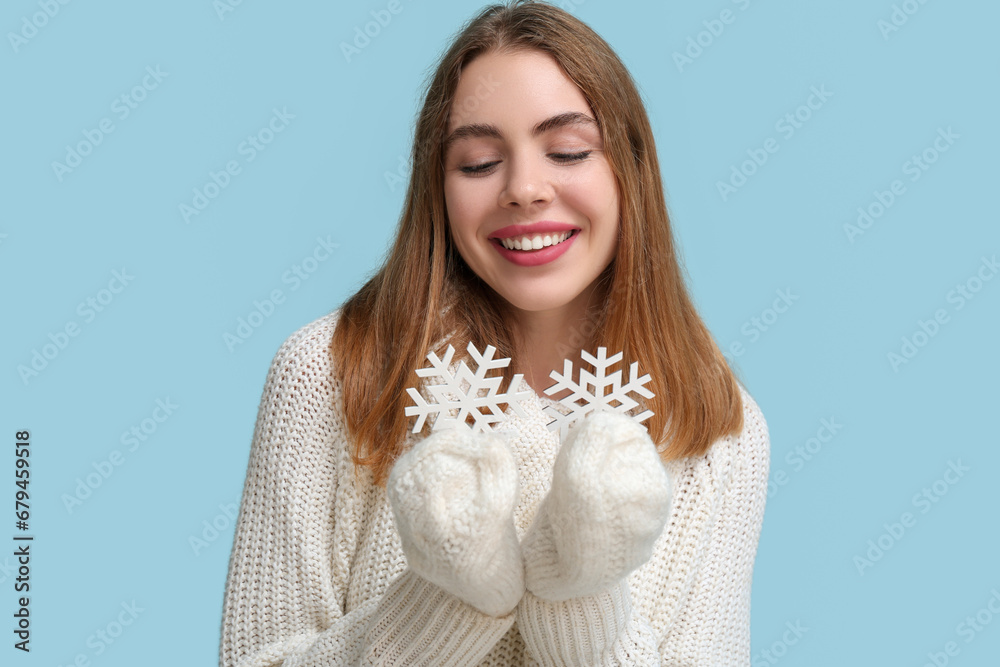 Happy young woman with decorative snowflakes on blue background