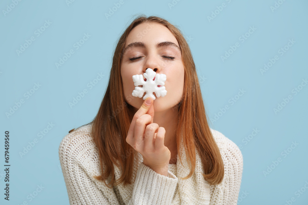 Beautiful young woman with decorative snowflake on blue background