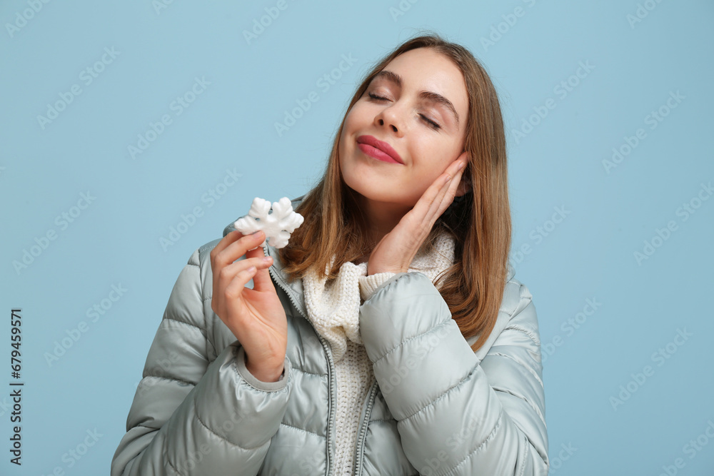 Beautiful young woman with decorative snowflake on blue background