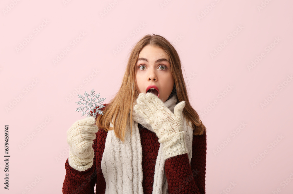 Shocked young woman with decorative snowflake on pink background