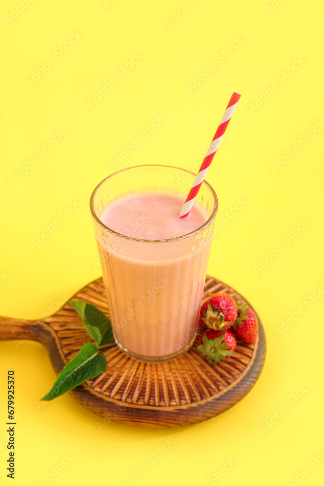 Glass of tasty strawberry smoothie on yellow background