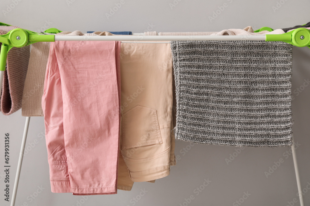 Clean winter clothes hanging on dryer near light wall