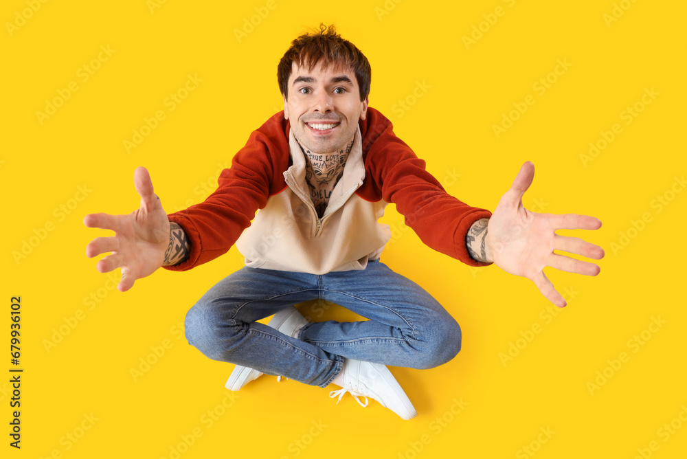 Young man opening arms for hug on yellow background