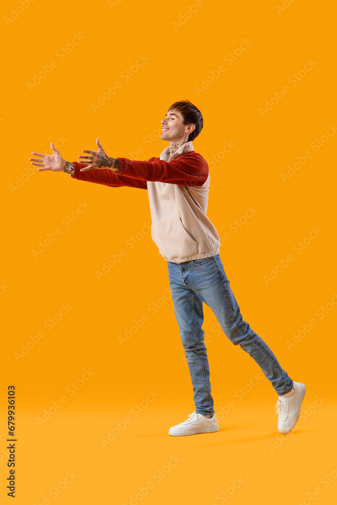 Young man opening arms for hug on yellow background