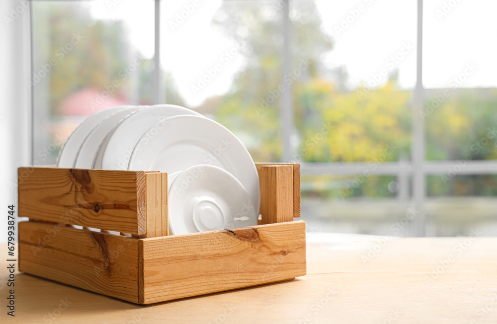 Holder with clean dishes on table in kitchen