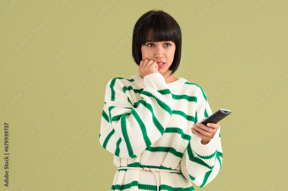 Young woman watching TV on green background