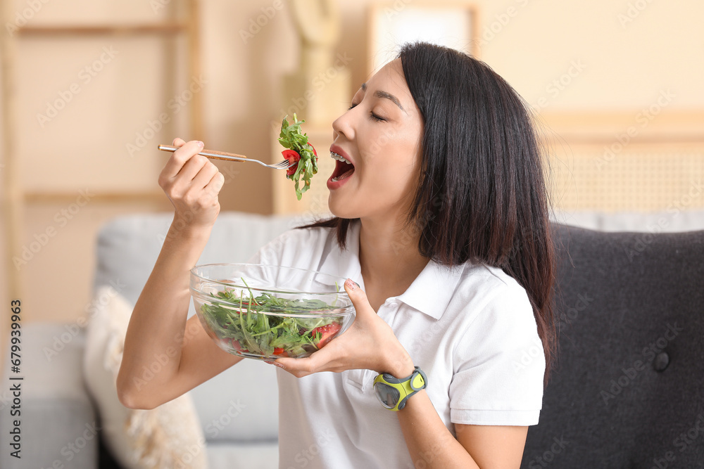 Beautiful young Asian woman with bowl of fresh vegetable salad at home. Weight loss concept