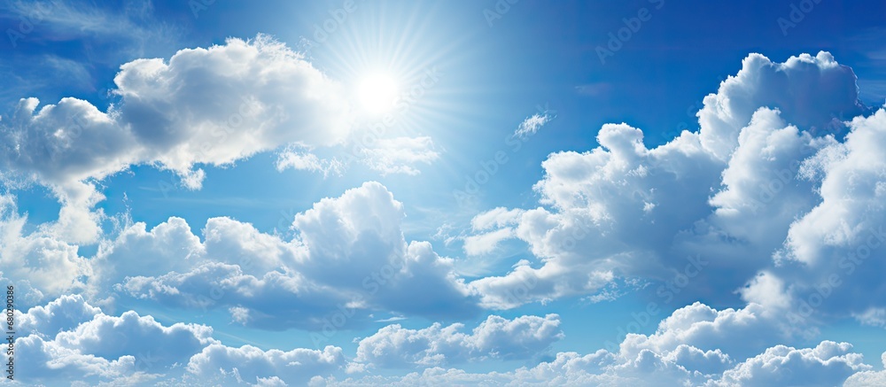 The beautiful view of nature depicted a sky filled with fluffy clouds against a backdrop of a vibrant blue sky, the sunlight casting a golden hue on the cloudy but sunny day.