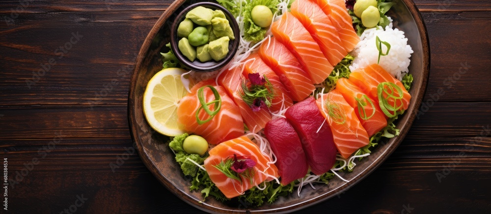 From a top view of the kitchen, a perfectly arranged plate of healthy Japanese food entices customers at the restaurant, featuring fresh sashimi, red fish, a zesty lemon, and a vibrant salad