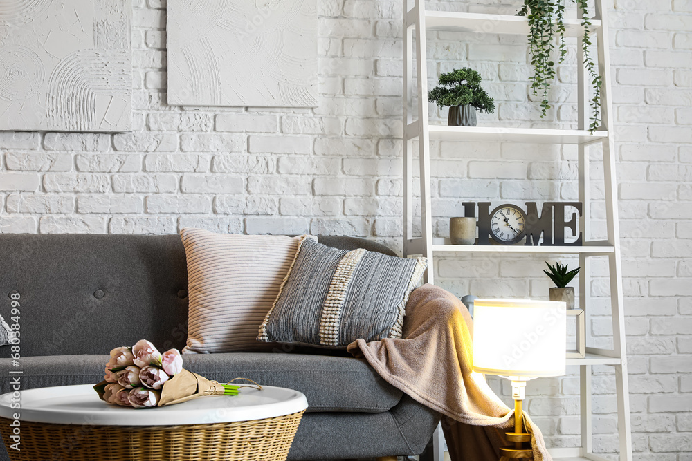 Interior of living room with cozy grey sofa and glowing lamp