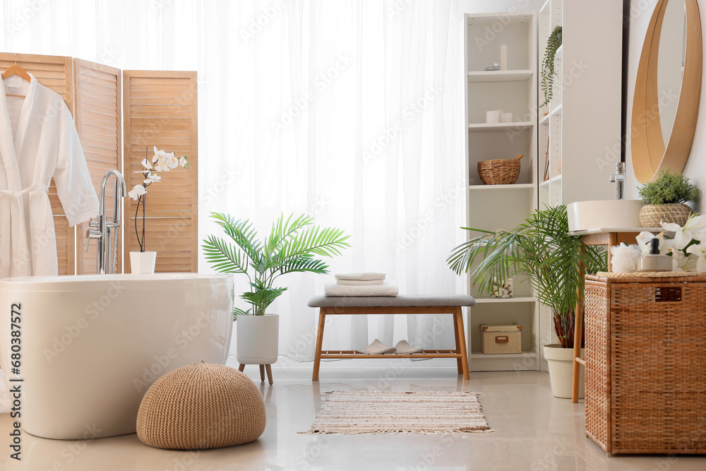 Interior of light bathroom with grey bench and bathtub