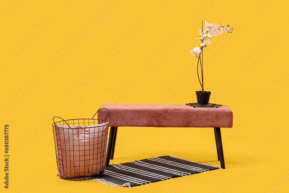 Pink bench with flowers and basket on yellow background