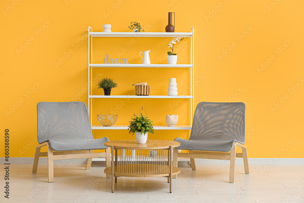 Modern shelf unit with grey chairs and table near orange wall