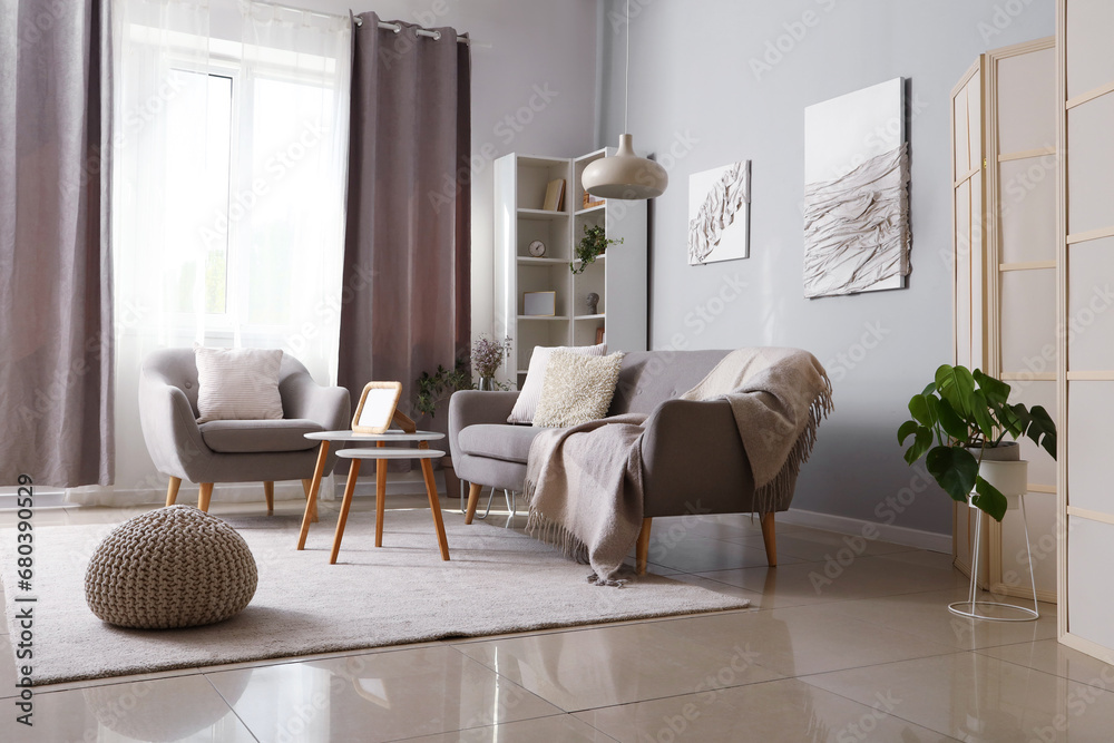 Interior of modern living room with grey sofa, armchair and coffee table