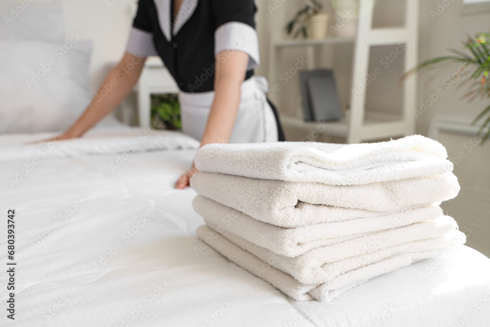 Chambermaid making bed in hotel room, closeup