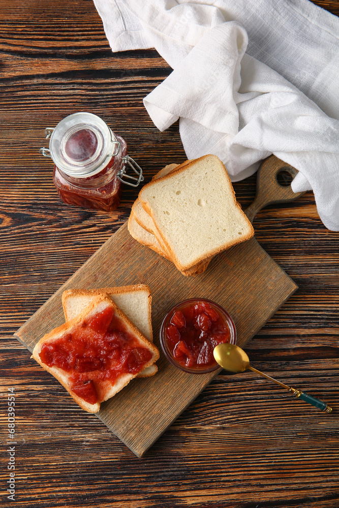 Board with delicious quince jam toasts on wooden background