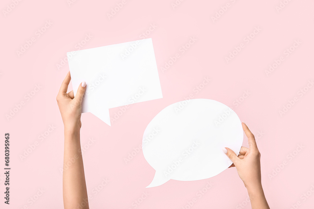 Female hands with blank speech bubbles on pink background