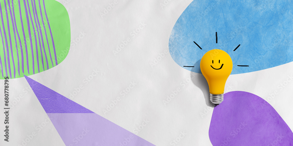 Yellow light bulb with happy face - flat lay