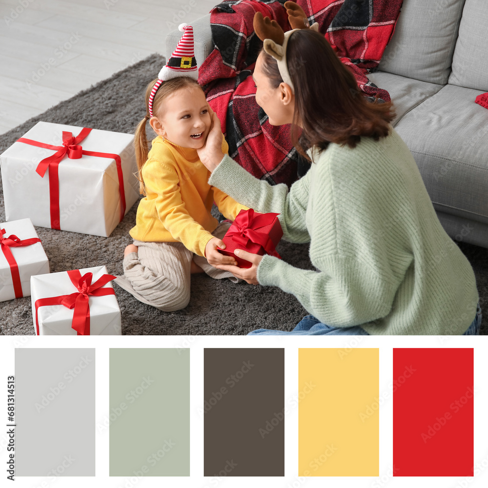 Young mother giving her little daughter Christmas gifts at home