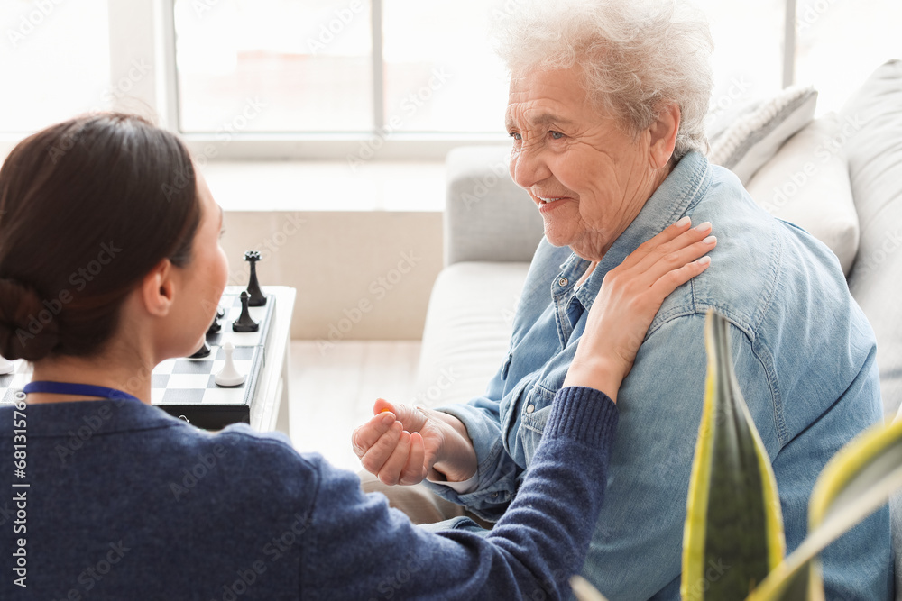 Senior woman taking pill from caregiver at home