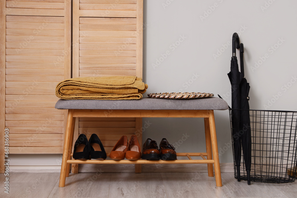 Bench with shoes, umbrellas and folding screen in hallway