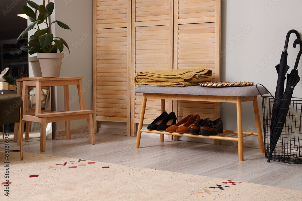 Bench with shoes, umbrellas and folding screen in hallway