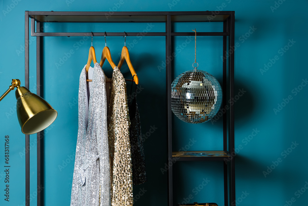 Shelving unit with clothes and disco ball near blue wall in room