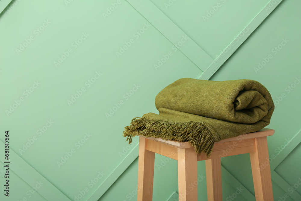 New soft folded blanket on chair near green wall