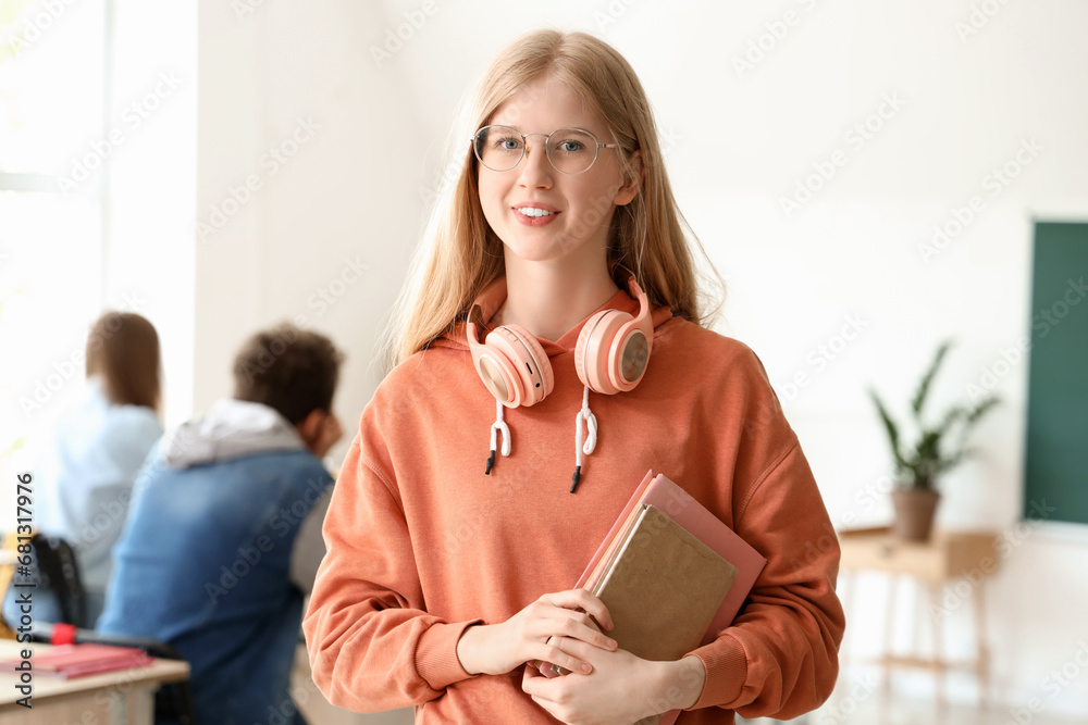 Female student with books and headphones in classroom