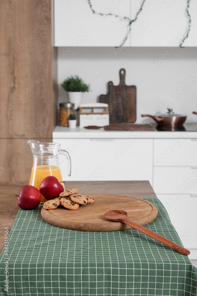 Wooden cutting board with food and drink on table in kitchen