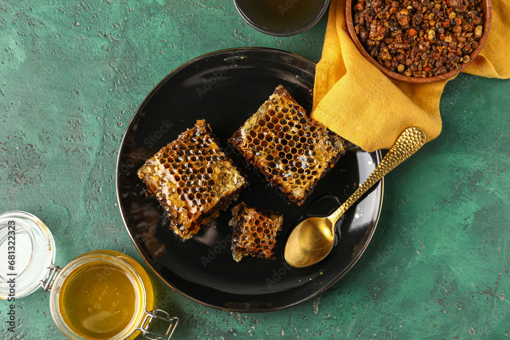 Plate with sweet honeycombs on green background