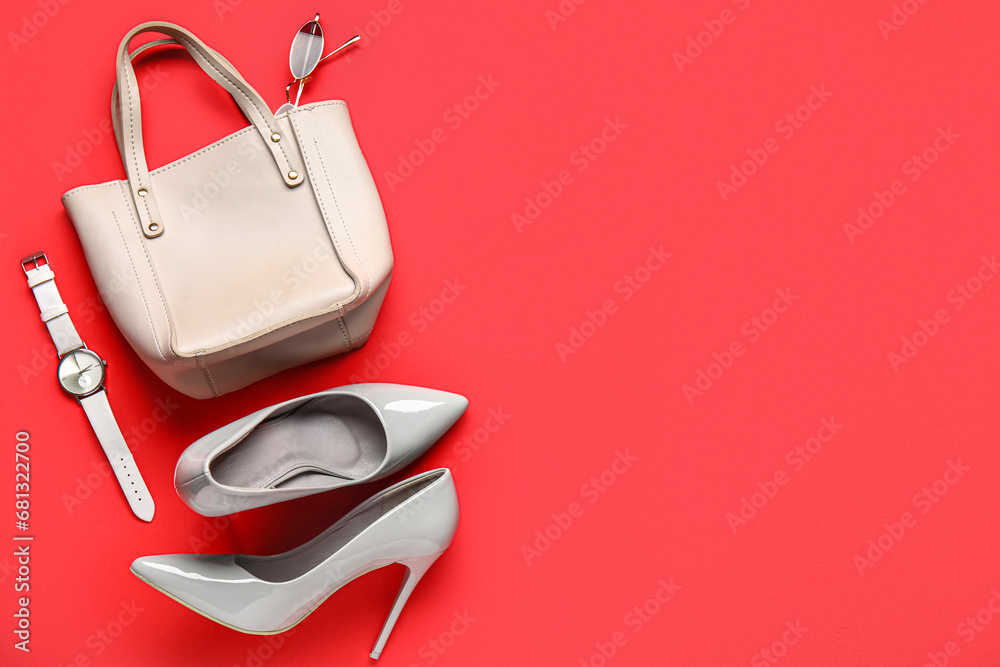 Composition with stylish female shoes, handbag and wristwatch on red background