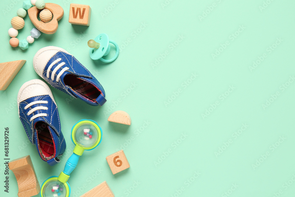 Stylish baby shoes with rattles, pacifier and cubes on turquoise background