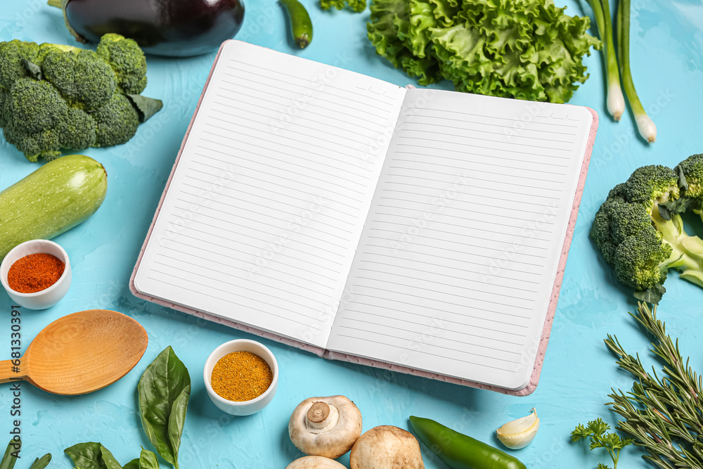 Composition with blank open recipe book, fresh vegetables and spices on color background