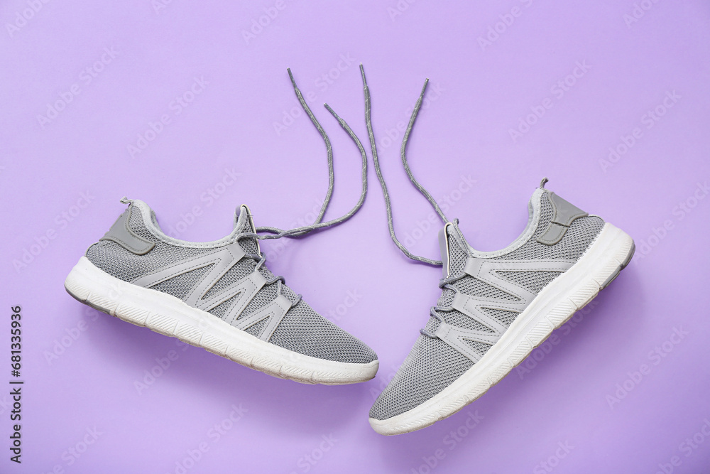 Stylish grey sneakers on purple background