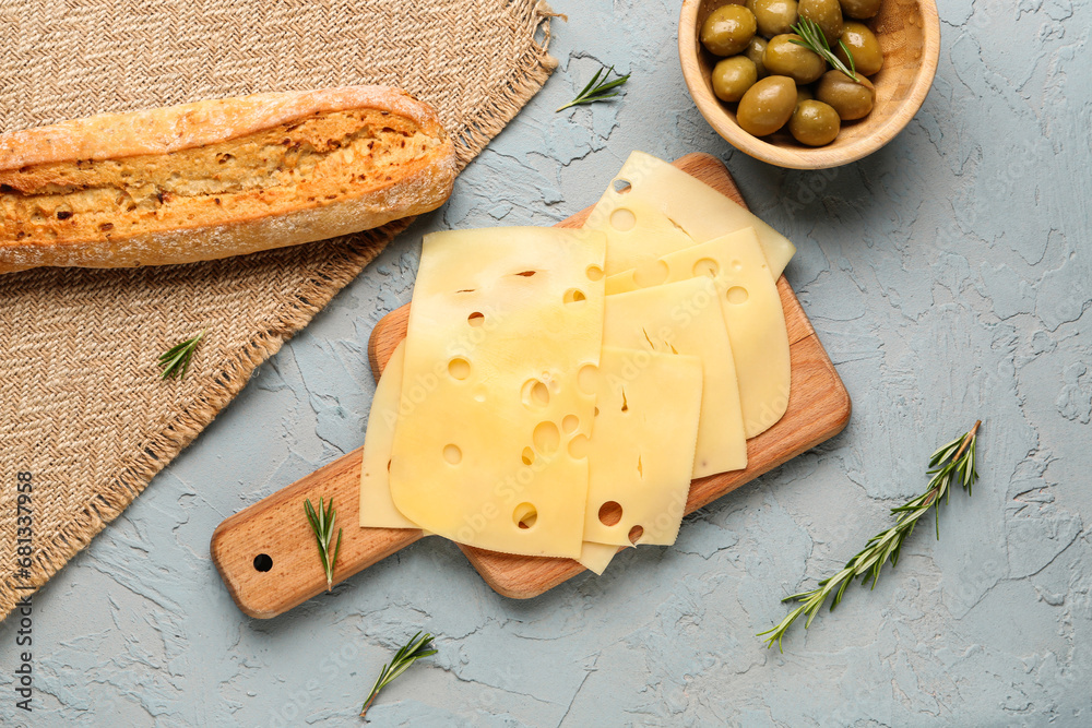 Board with tasty cheese slices, olives and baguette on light background