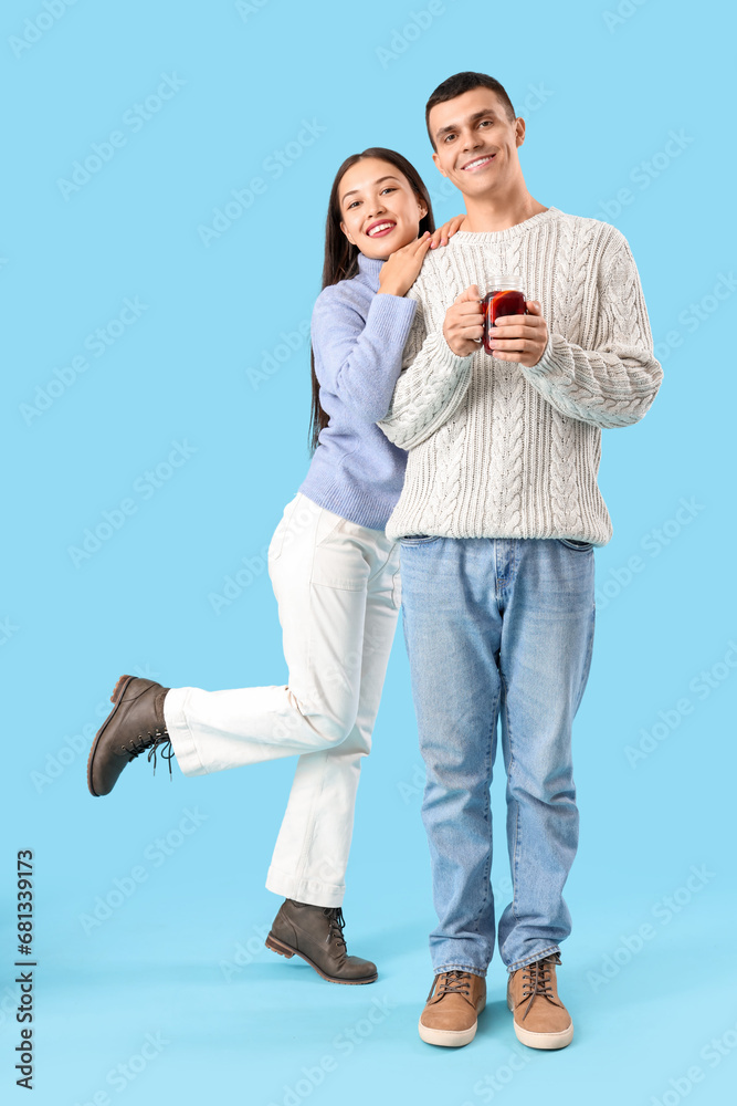 Happy couple with glass of warm mulled wine on blue background