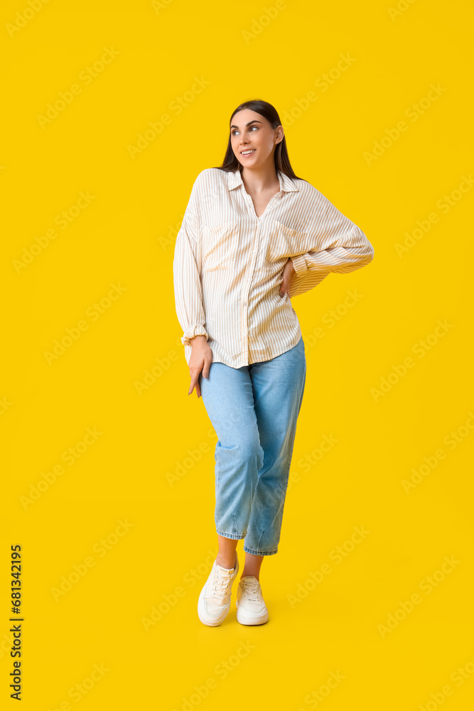 Beautiful young woman in stylish white sneakers and cardboard box with high heels on yellow background