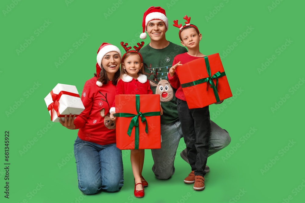 Happy family in Christmas clothes and gifts on green background