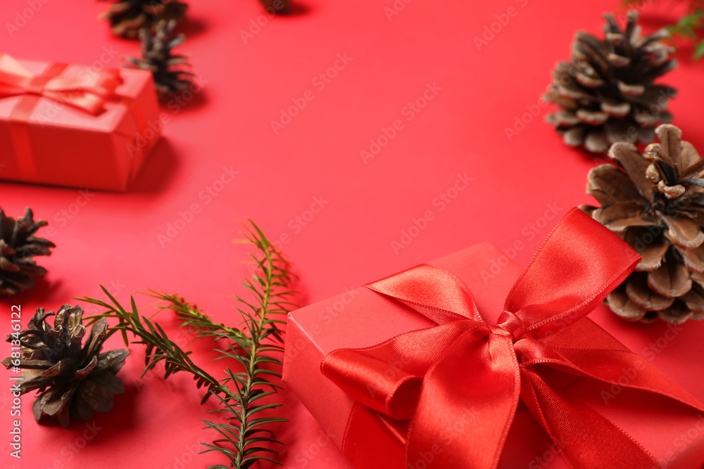 Pine cones with fir branch and Christmas gift boxes on red background